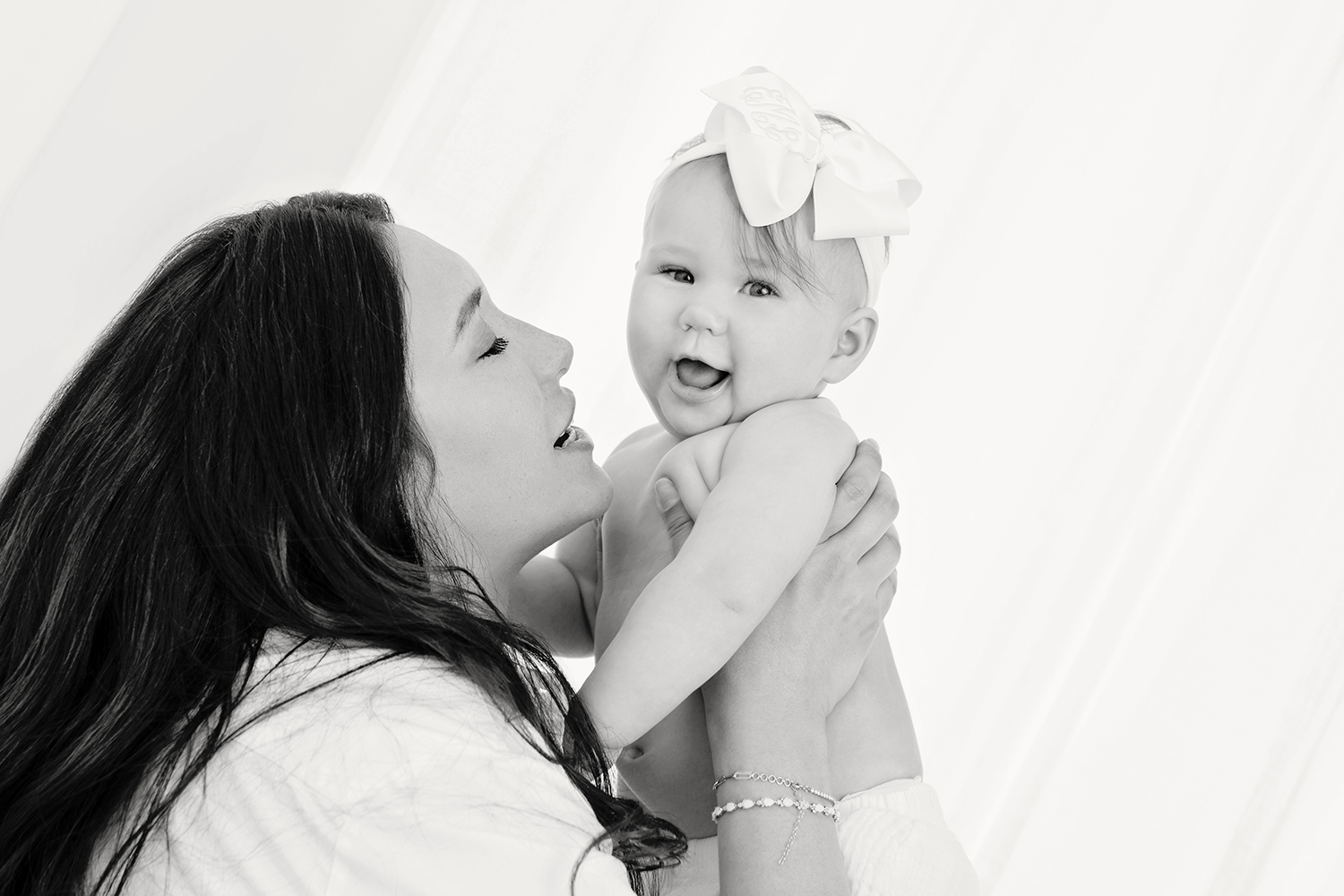 a black and white photo of a mother caressing her baby girl