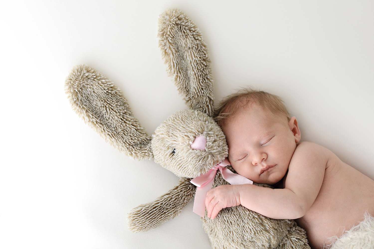 a sleeping baby holding a stuffed animal