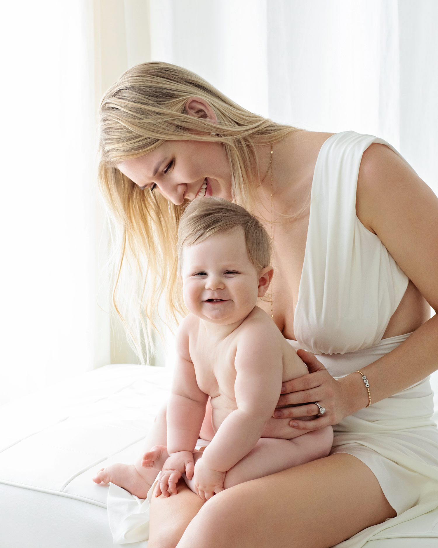 A mother cuddles her newborn who is smiling