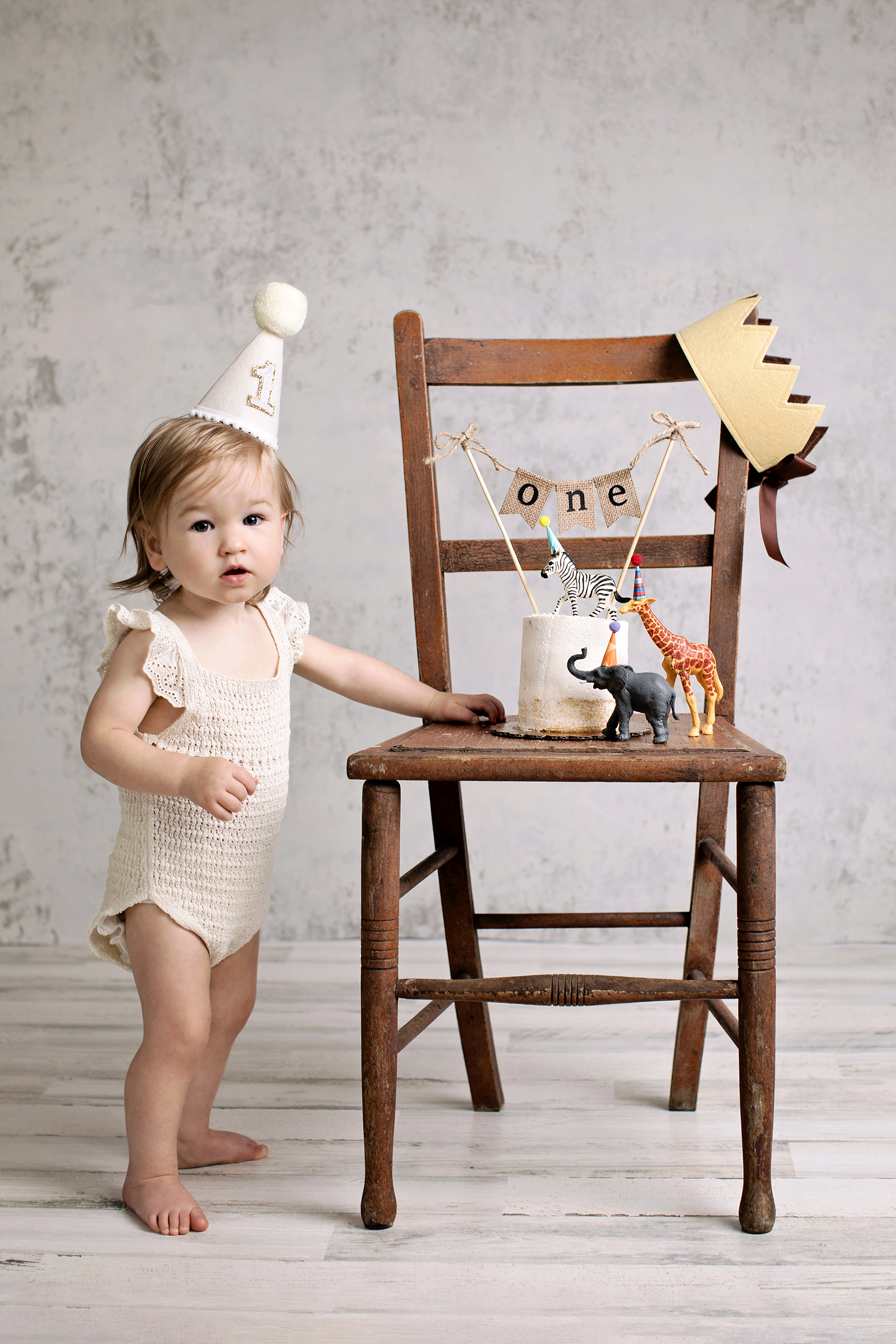 first birthday milestone image of baby with cake on antique chair