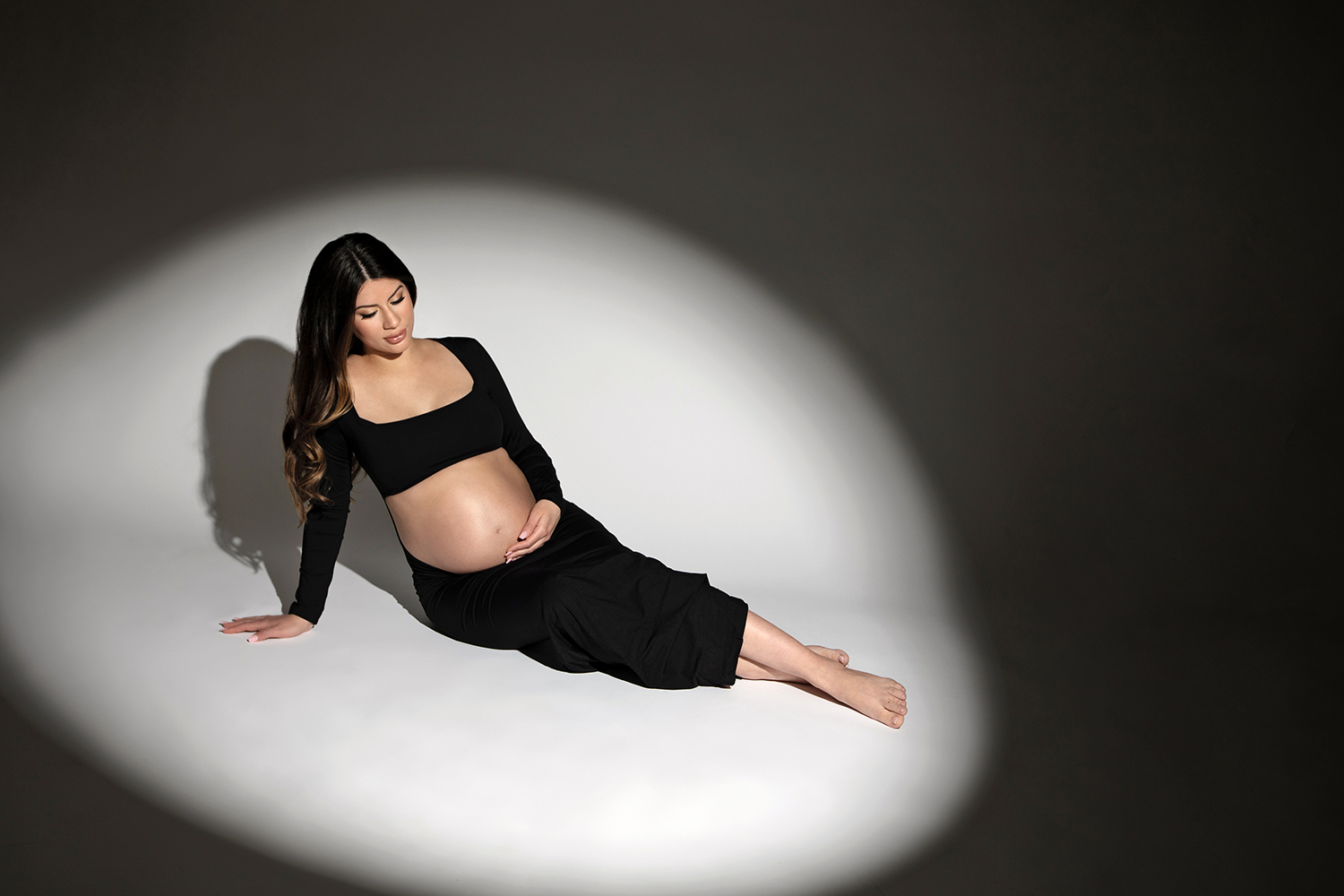 A confident woman rocks a bold black two piece set in a maternity photoshoot