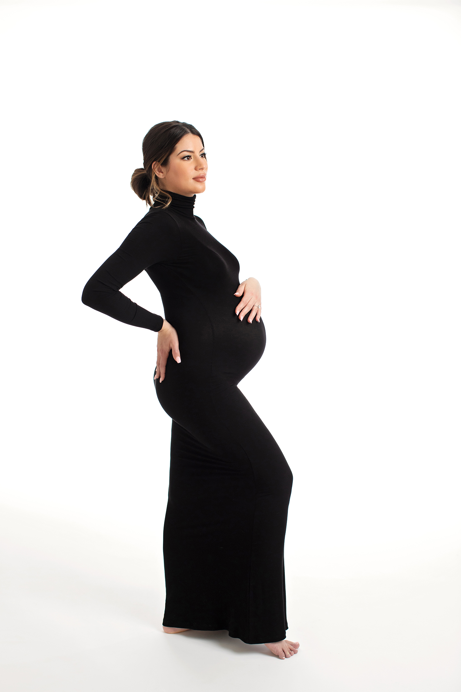 A confident woman rocks a bold black outfit in a maternity photoshoot