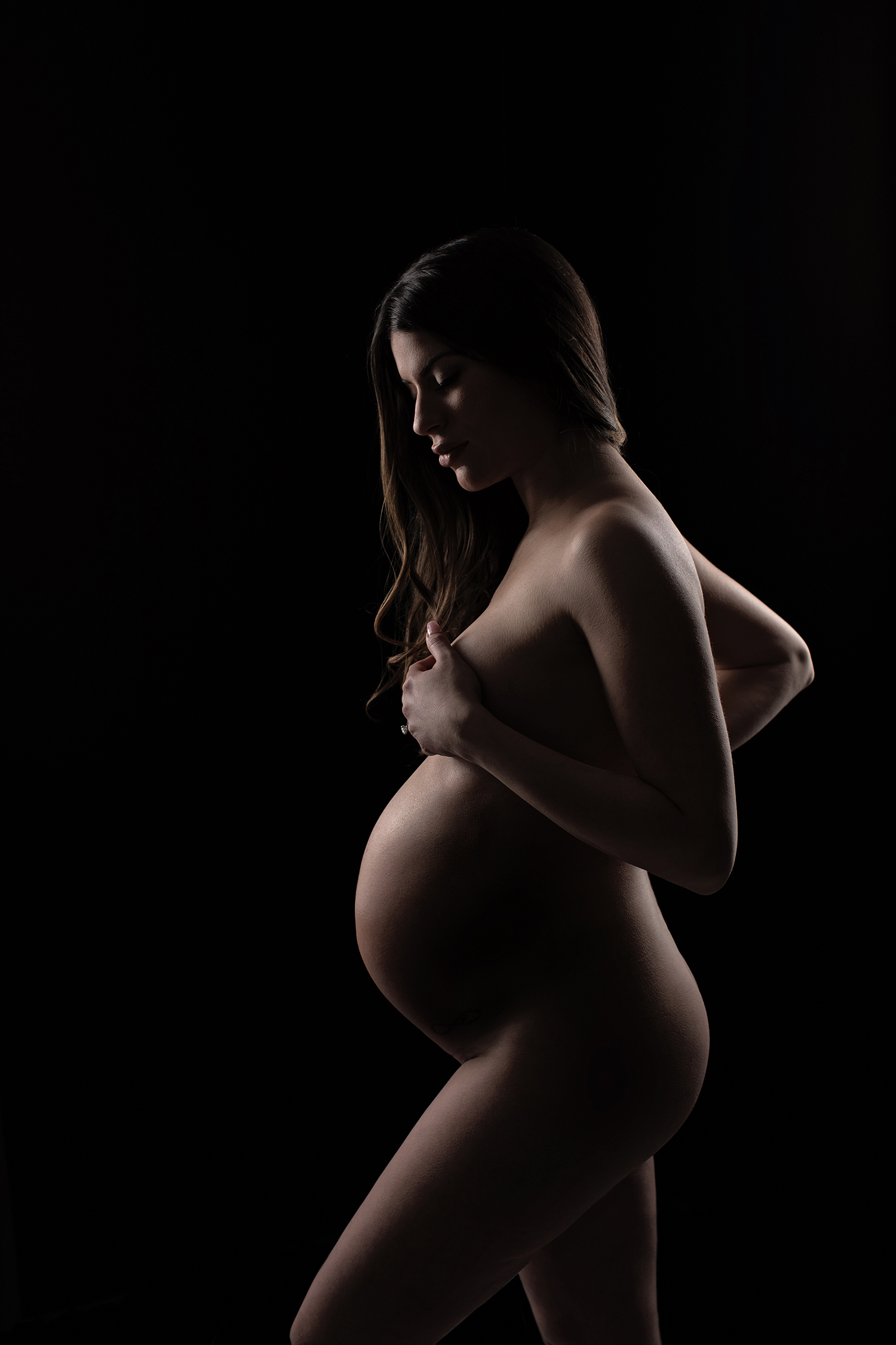 a dramatic backlit shot of a pregnant woman