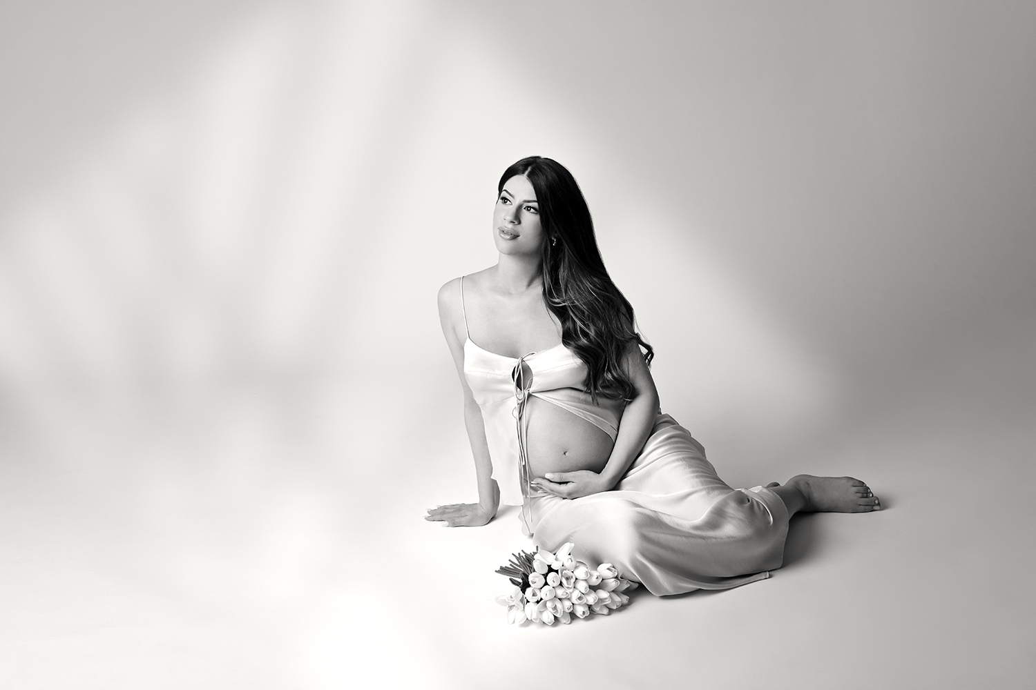 A maternity photo session featuring a woman draped in luxurious fabrics and fitting on the ground