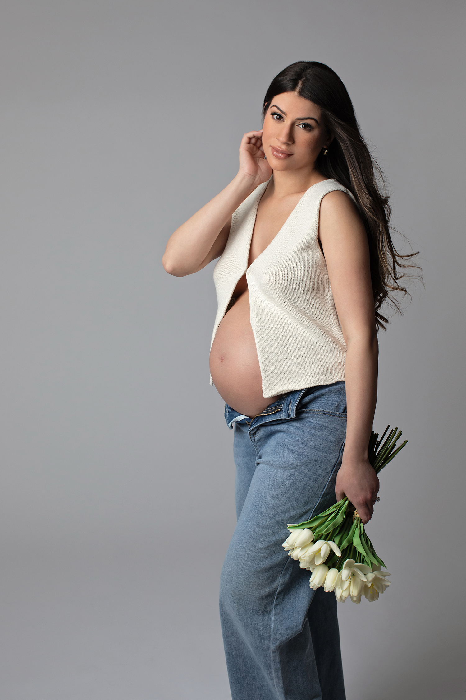 a pregnant woman in a casual outfit holding flowers