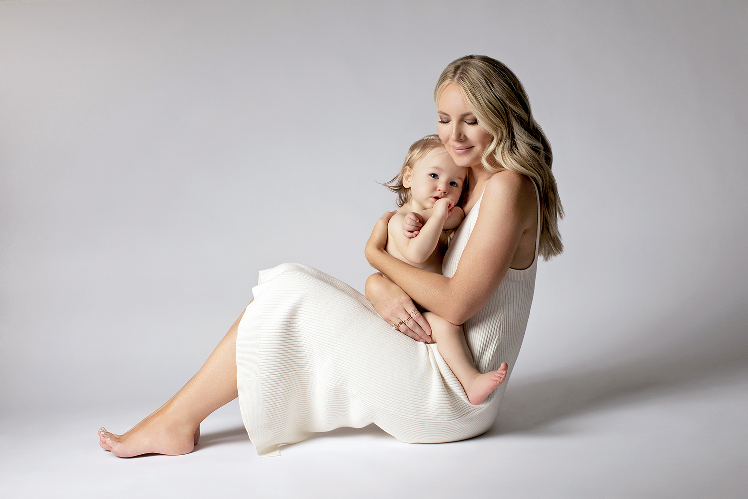 Mom and baby cuddle in a relaxed studio motherhood photography session